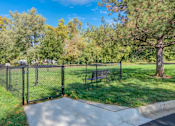 Thumbnail 16 of 18 - A black fence surrounds a park bench in the middle of a grassy area.