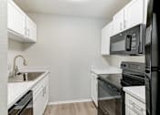 Thumbnail 2 of 18 - A kitchen with black appliances and white cabinets.