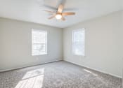 Thumbnail 12 of 18 - A room with a ceiling fan and two windows.