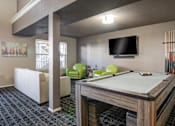 Thumbnail 9 of 18 - A billiard table is in the middle of a room with a TV and a chair.