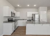 Thumbnail 16 of 36 - an empty kitchen with white cabinets and granite counter tops at Hillcrest Village, Springdale, AR