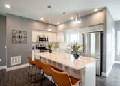 Thumbnail 1 of 18 - A modern kitchen with a large island and wooden chairs.