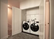 Thumbnail 5 of 18 - A laundry room with two washing machines and a white door.