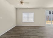 Thumbnail 13 of 36 - an empty living room with a ceiling fan and a window at Hillcrest Village, Arkansas