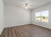 Thumbnail 15 of 36 - an empty living room with a ceiling fan and a window at Hillcrest Village, Springdale, AR 72762