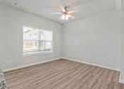 Thumbnail 14 of 36 - an empty living room with a ceiling fan and a window at Hillcrest Village, Arkansas, 72762