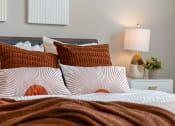 Thumbnail 4 of 36 - a bed with red and white pillows and a brown blanket at Hillcrest Village, Springdale Arkansas
