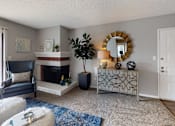 Thumbnail 5 of 34 - A living room with a fireplace, a chair, a mirror, and a plant.