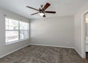 Thumbnail 12 of 36 - A room with a ceiling fan and carpeted floor.