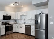 Thumbnail 3 of 36 - A kitchen with white cabinets and a black fridge.