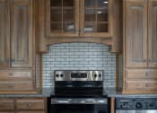 Thumbnail 10 of 50 - a kitchen with wood cabinets and a black stove top oven