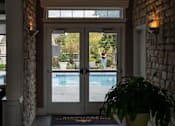 Thumbnail 5 of 44 - A woman is standing in the doorway of a house with a pool in the backyard.