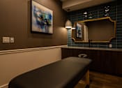 Thumbnail 16 of 44 - a massage table in a room with a mirror  at The Clearing at ONE28, Olathe, KS, 66062