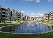 Thumbnail 2 of 44 - a large pond with a fountain in front of an apartment building at The Clearing at ONE28, Olathe