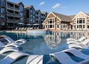 Thumbnail 13 of 44 - a large pool with white chairs in front of an apartment building at The Clearing at ONE28, Olathe, 66062