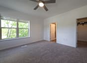 Thumbnail 37 of 44 - an empty living room with a large window and a ceiling fan at The Clearing at ONE28, Olathe