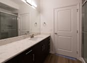 Thumbnail 33 of 44 - a bathroom with a sink and a mirror and a shower at The Clearing at ONE28, Olathe