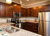 Thumbnail 13 of 59 - A kitchen with a stainless steel refrigerator and wooden cabinets.