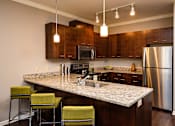 Thumbnail 12 of 59 - A kitchen with a granite countertop and stainless steel appliances.