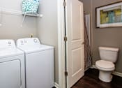 Thumbnail 26 of 59 - A small laundry room with a toilet and washer.