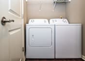 Thumbnail 27 of 59 - A white washing machine and dryer in a small laundry room.