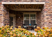 Thumbnail 31 of 59 - A patio with a table and chairs is framed by a brick wall.
