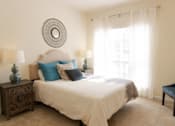 Thumbnail 33 of 44 - A bedroom with a bed, two lamps, a chair, and a mirror on the wall. at The Crest at Sugarloaf, Lawrenceville