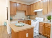 Thumbnail 31 of 44 - A kitchen with wooden cabinets and a white stove top oven. at The Crest at Sugarloaf, Lawrenceville, 30044