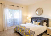 Thumbnail 23 of 44 - A bedroom with a large bed and a round mirror on the wall. at The Crest at Sugarloaf, Lawrenceville, GA, 30044