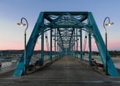 Thumbnail 59 of 66 - a bridge over the water at sunset with benches on it at District at Riverside Apartments, Tennessee, 37406