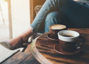 Thumbnail 58 of 66 - two cups of coffee sitting on a table next to a person at District at Riverside Apartments, Chattanooga, Tennessee