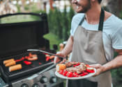 Thumbnail 54 of 60 - a man holding a plate of food in front of a grill at The Crest at South Point, McDonough, 30253