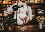 Thumbnail 62 of 66 - a man pouring wine into a glass in a bar at District at Riverside Apartments, Tennessee, 37406
