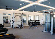 Thumbnail 46 of 60 - A gym with a variety of equipment including treadmills, weights, and a bench press at The Crest at South Point Apartments, McDonough, Georgia