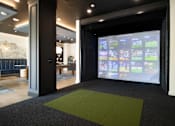 Thumbnail 36 of 60 - A room with a green carpet and a screen with images on it. at The Crest at South Point Apartments, McDonough, GA, 30253