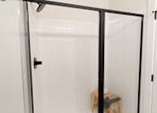 Thumbnail 8 of 66 - A glass shower door with a black handle.