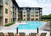 Thumbnail 3 of 72 - A large swimming pool surrounded by lounge chairs and apartment buildings.