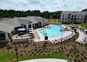 Thumbnail 1 of 60 - A large outdoor swimming pool surrounded by a black fence and a building in the background at The Crest at South Point Apartments, Georgia, 30253