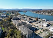 Thumbnail 50 of 66 - A large building complex sits in front of a body of water with a parking lot in front of it.at District at Riverside Apartments, Chattanooga