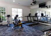 Thumbnail 10 of 44 - A home gym with a variety of equipment including treadmills, stationary bikes, and weights. at The Crest at Sugarloaf, Lawrenceville