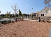 Thumbnail 29 of 54 - a fenced in dog park with a bench and a building in the background at The Crest at Acworth, Acworth, GA