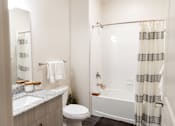 Thumbnail 9 of 30 - Bathroom with white subway tile and striped shower curtain at The Crest at Acworth Apartments, Acworth, GA