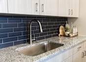 Thumbnail 3 of 30 - Modern kitchen sink with dark tile backsplash at The Crest at Acworth Apartments, Acworth