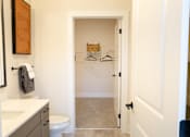 Thumbnail 17 of 66 - A bathroom with a toilet, sink, and a closet with a hanger.at District at Riverside Apartments, Tennessee, 37406
