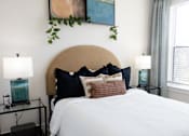 Thumbnail 20 of 66 - A bed with a white comforter and a brown headboard with black pillows.at Riverside Apartments, Chattanooga, TN