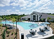 Thumbnail 1 of 27 - A large outdoor swimming pool with a building in the background.