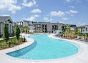 Thumbnail 2 of 27 - A large outdoor swimming pool surrounded by lounge chairs and umbrellas.
