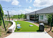 Thumbnail 4 of 27 - A playground area with a slide and a green lawn.