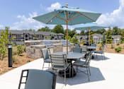 Thumbnail 6 of 27 - A patio with a table and chairs under an umbrella.