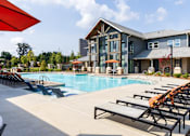 Thumbnail 23 of 30 - Resort style pool with lounge chairs and clubhouse at The Crest at Acworth Apartments, Acworth